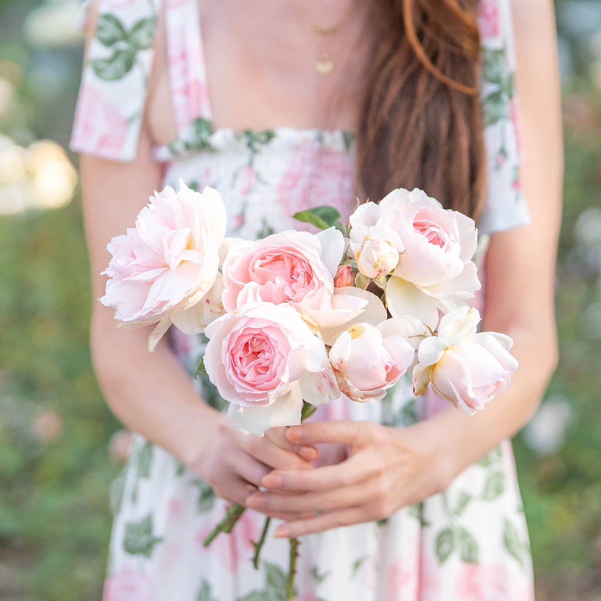 Woman holding a bouquet of pink flowers in a garden setting